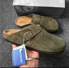 Birkenstock Boston clogs in a green suede with a Stüssy collaboration logo